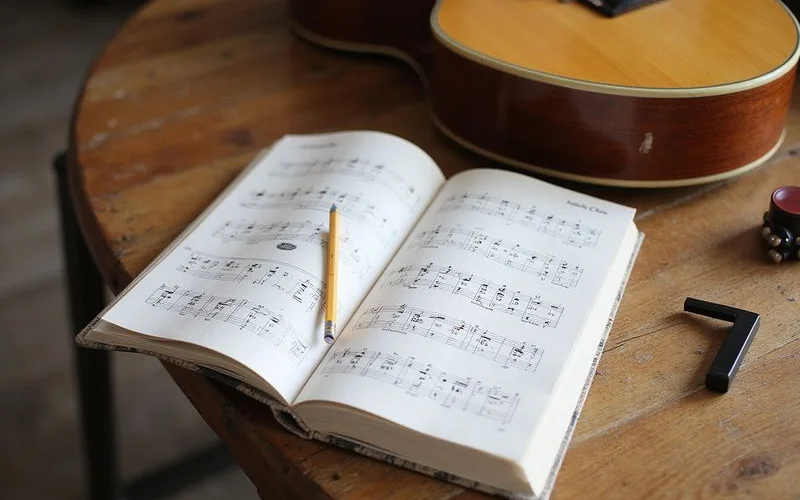 An open songbook of chord charts beside an acoustic guitar
